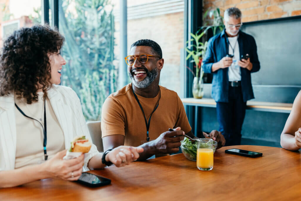 Colleagues enjoying a casual lunch break while sharing laughter and eating healthy food